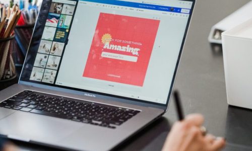 Person using a laptop and graphic tablet for digital design work in a home office.
